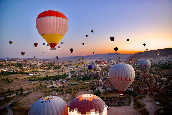 Dozens of hot air balloons floating over Cappadocia valleys at sunrise_edited