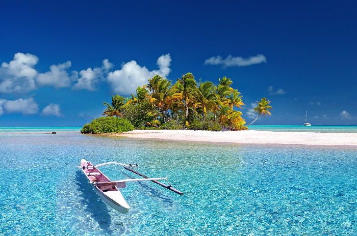 Small tropical island with palm trees and turquoise lagoon