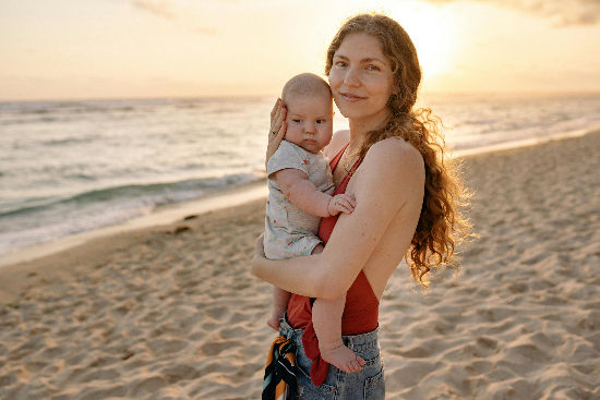 Mother holding baby at sunset on family beach vacation_edited