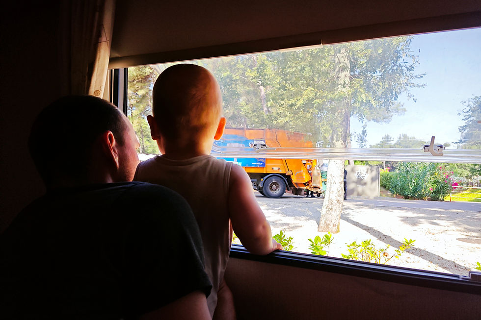 Mann und Kleinkind schauen aus dem Wohnwagen Fenster