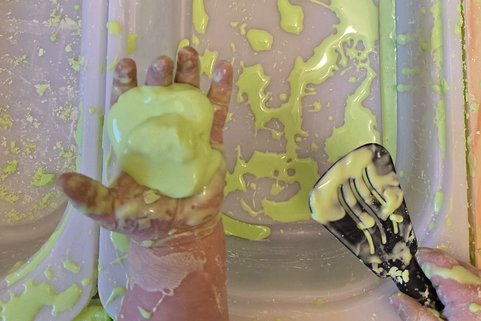Hände eines Kindes beim Spielen mit Oobleck; in der rechten Hand hält das Kind einen Kinder-Pfannenwender, mit der linken Hand greift es direkt in die Masse.