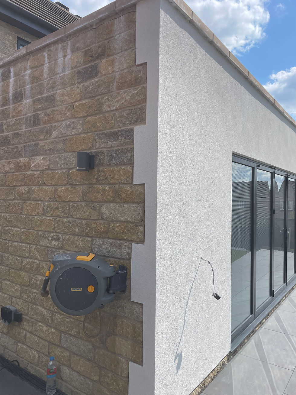 Decorative white silicone render finish on a modern extension in Aston, S26, featuring sharp corner beads and clean lines.