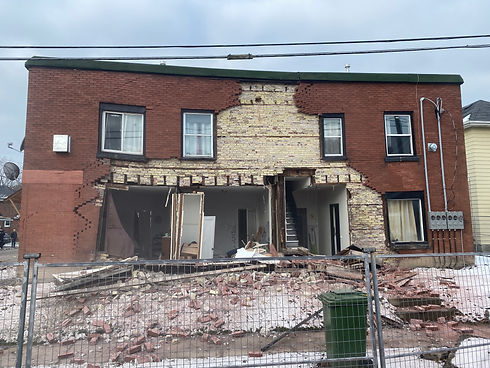 A building that is in the middle of being knocked down, with construction fencing around it