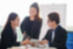 Three business professionals collaborating and sharing perspectives during a leadership meeting