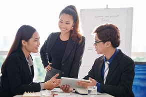 Three business professionals collaborating and sharing perspectives during a leadership meeting