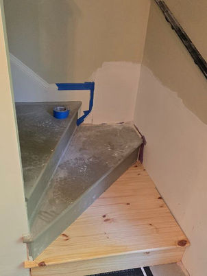 Staircase renovation in progress with new wooden treads and partial drywall repair.