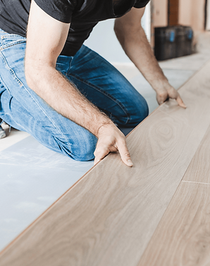Handyman installing laminate flooring during a home renovation project.