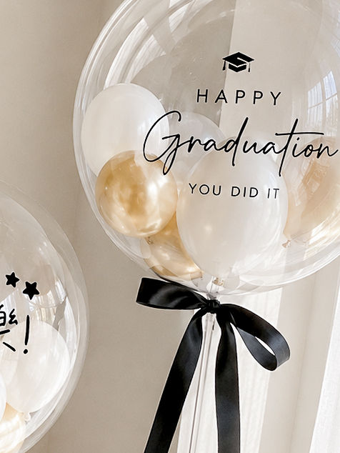 縮圖：圖片替代文字： 展示一顆專為畢業季設計的客製化白金配色氣球波波球。這顆透明波波球內部裝滿了白色氣球與金色氣球（呈現白金相間的效果），呈現出法式輕奢的高級感。球體上印有精緻的繁體中文祝賀語「畢業快樂！」與愛心印花。