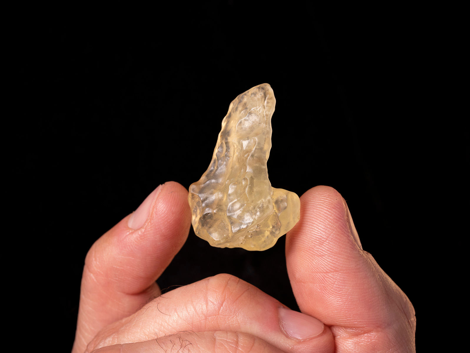Vista fotografía frontal vidrio desierto Libia sujeto por una mano para mostrarlo.