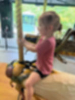 Little girl rides the bug carousel at the Bronx Zoo