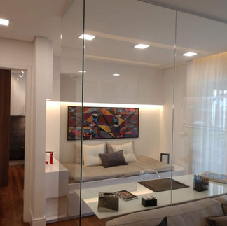 Dois espelhos grandes instalados na sala, um na parede lateral e outro na parede frontal formando uma união que amplia o ambiente com sofisticação