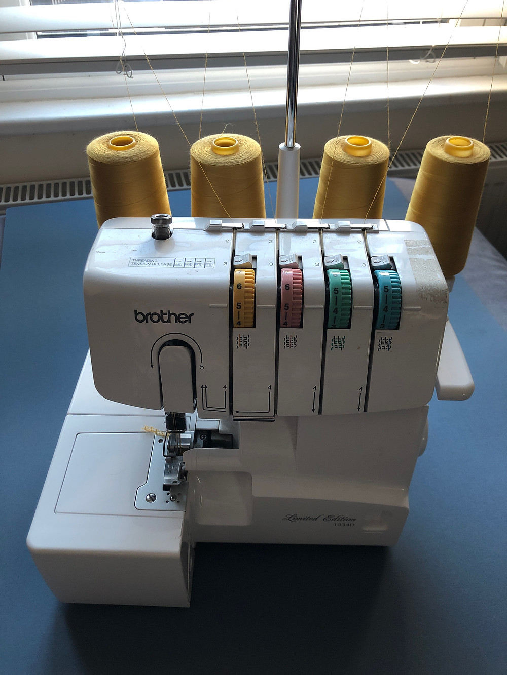 Brother 1034D Overlocker in front of a window on blue mountboard