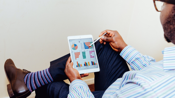 man in striped short looking at graphs on tablet