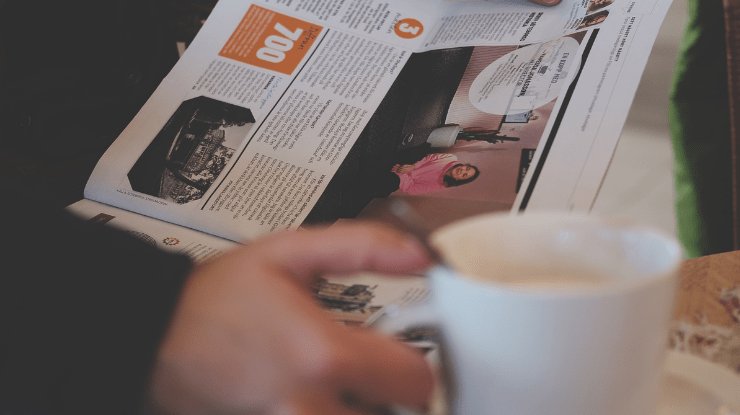 a man enjoying a coffee and a local newspaper