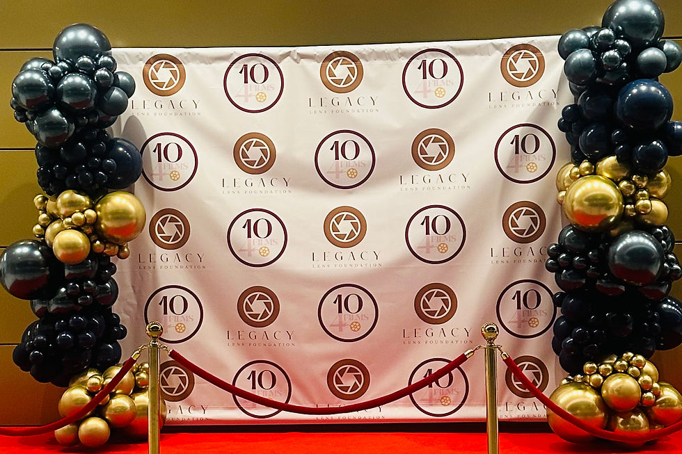 Black and gold balloon columns framing a branded step-and-repeat backdrop with red carpet