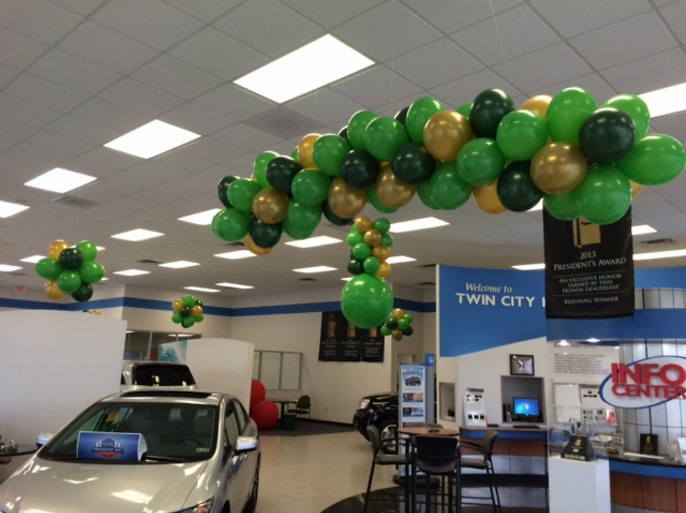 Car dealership showroom decorated with pink and white ceiling balloon topiaries for a prom