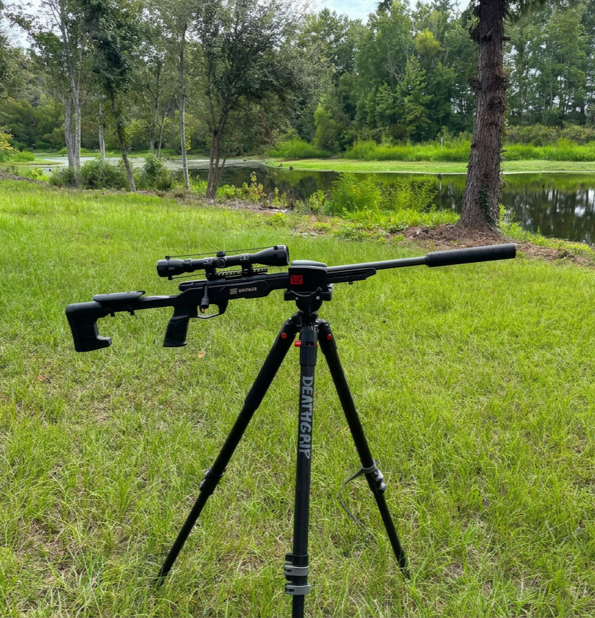 The genesis suppressor on a bolt action rifle resting on a tripod in the woods