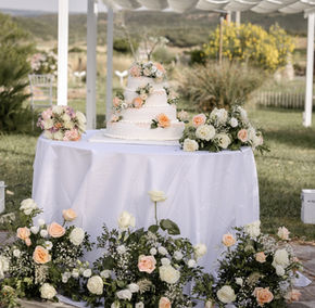 Torta nuziale bianca con fiori rosa e pesca, all'aperto.
