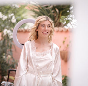 Sposa sorridente in vestaglia di raso bianco