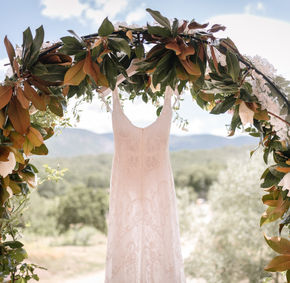 Abito da sposa appeso a un arco floreale all'aperto