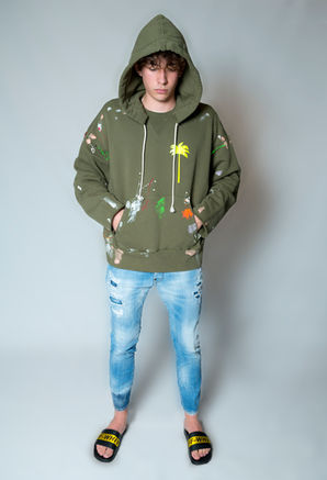 Ragazzo con felpa verde macchiata e jeans strappati