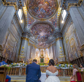 Sposi inginocchiati in una chiesa riccamente decorata.