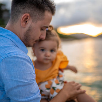 Padre che tiene in braccio la figlia al tramonto