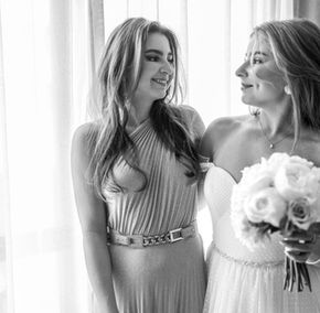 La sposa con un bouquet e la damigella sorridono.