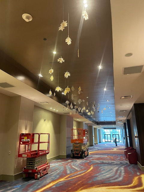 Suspended leaf art installation adds an enchanting touch to the hotel lobby, with delicate foliage hanging elegantly from the ceiling.