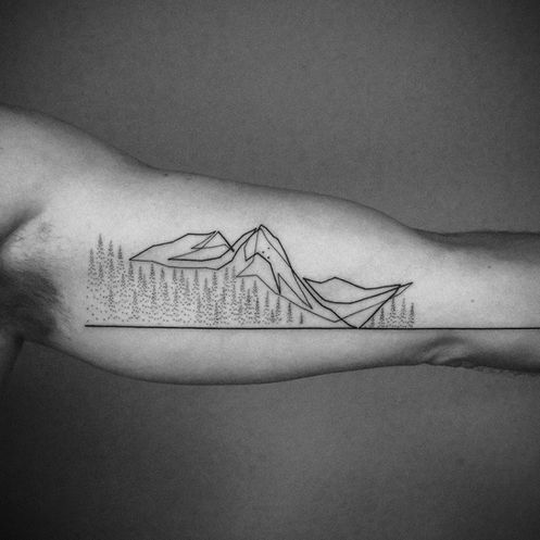  Minimalist mountain landscape tattoo on a man's bicep, created by Mo Ganji. The design features geometric mountain shapes, a single-line horizon, and dotted pine trees—hallmarks of Mo Ganji’s clean single-line and dotwork tattoo style.