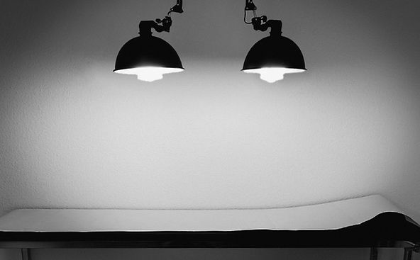 Schwarz-weiß-Foto eines vorbereiteten Tattootisches unter zwei Lampen im Berliner Studio von Mo Ganji, bekannt für seine minimalistischen One-Line-Tattoos und ruhige, konzentrierte Sitzungen.