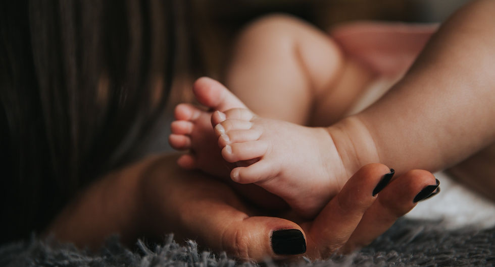 a mother's hand reaching softly to care for a baby's feet - Image by Pexels