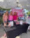Three women stand in the Breast Cancer Awareness booth