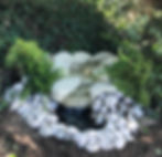 Large artificial garden waterfall feature with rock effect beside pond