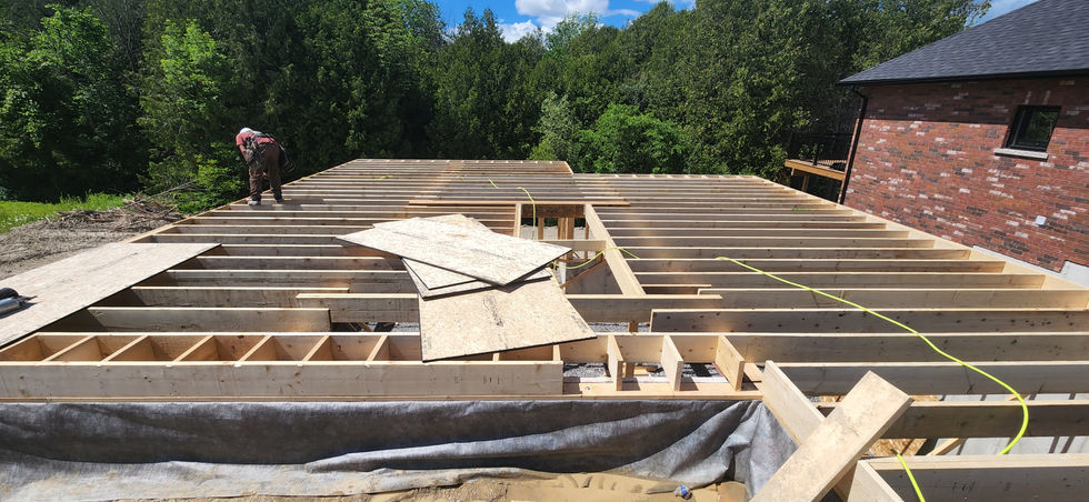 Construction site with wooden framework and trees nearby.