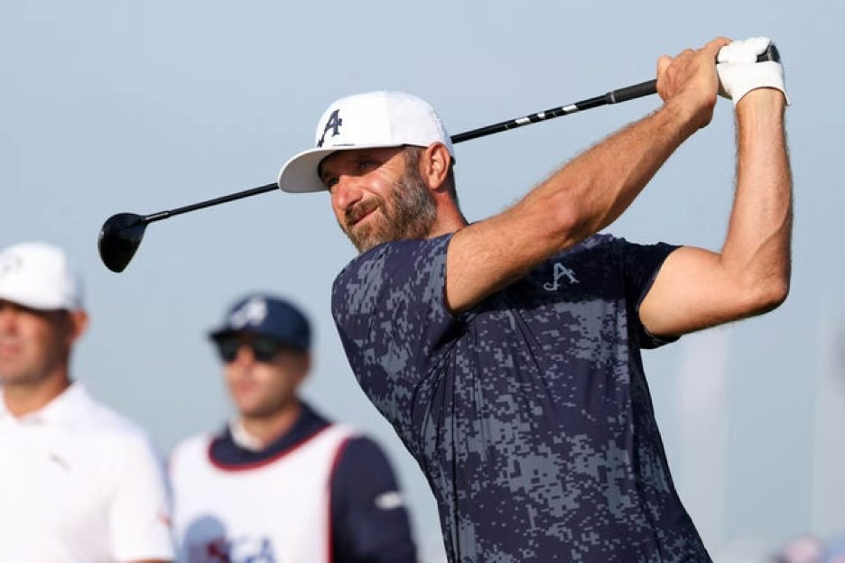 Golfer in white cap and navy camo shirt swings a driver on a sunny course, with two blurred players in the background.
