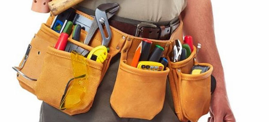Worker holding a hammer, wearing a tool belt and carrying a toolbox.