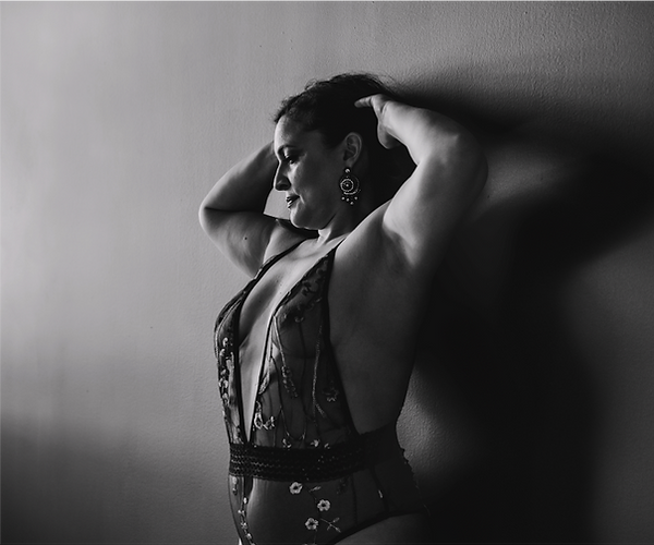 black and white photo of woman posing against wall