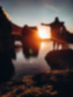 A romantic couple watches the sunset over the natural pools of Porto Moniz, Madeira. The crystal clear water reflects the orange and pink hues of the sunset, creating a serene and peaceful atmosphere. Perfect for a sunset swim or a romantic getaway.