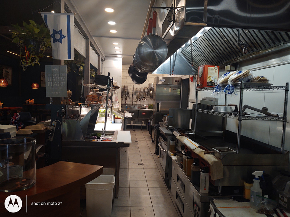 View of the alley kitchen in DonLeon's is visible.  The kitchen includes industrial equipment, pots & pans, and other food prep.