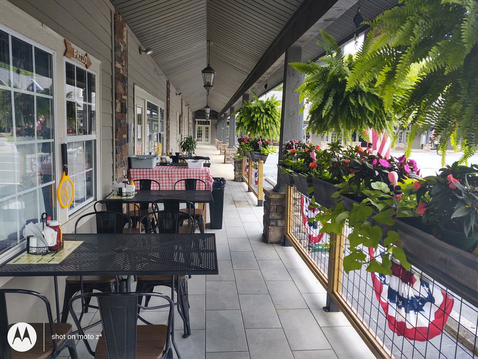 On the left, DonLeon's customers can sit at the outdoor tables and chairs. On the right, there is a fence with plants and greenery hanging. 