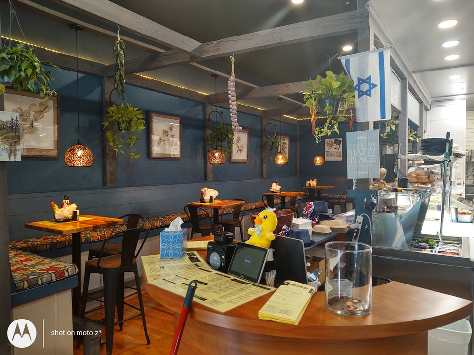 The order counter with a stuffed animal yellow duck is in front of the kitchen and includes multiple menu formats. The left-side dining area us also visible behind the order counter.