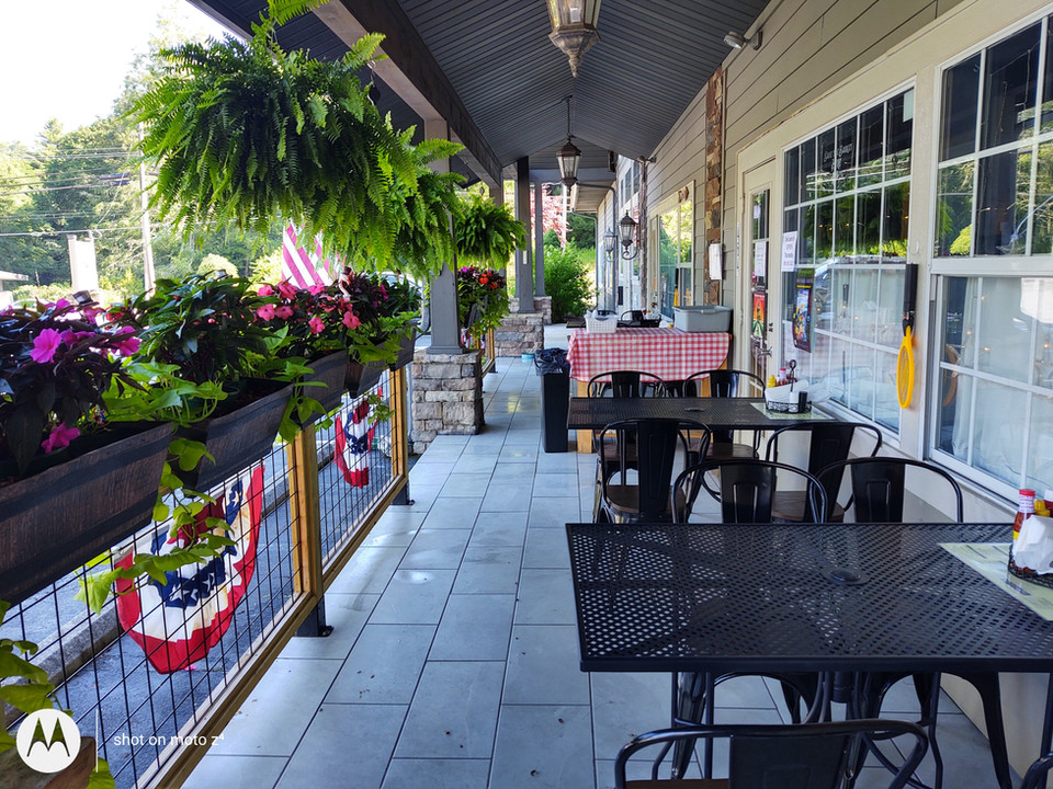 On the right, DonLeon's customers can sit at the outdoor tables and chairs. On the left, there is a fence with plants and greenery hanging. 