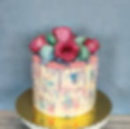 Tall textured buttercream drip cake with roses and macarons