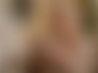 Elderly woman sitting comfortably in a cozy living room at Christmas, smiling while holding a warm mug with a softly lit Christmas tree in the background.