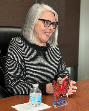 Melody Smith seated at a table during her interview with her Aging Well Award displayed in front of her, speaking about community and purpose.
