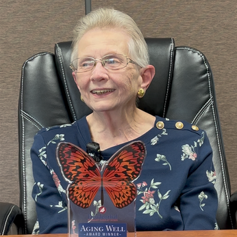 Martha Frank smiles while holding her butterfly-shaped Aging Well Award during her interview with Freudenthal Home-Based Healthcare.