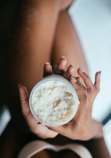 Woman using a natural and revitalizing plant-based body wash and exfoliating body polish.