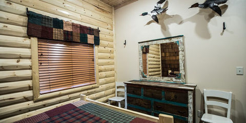 Rustic cabin bedroom with dresser, mirror, and ducks