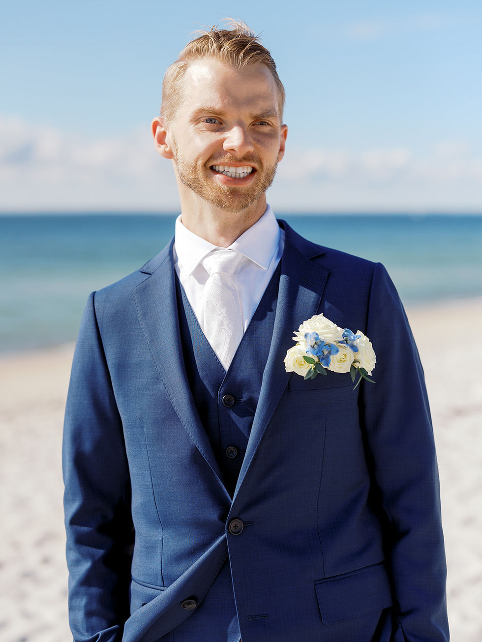 Groom with floral pocket square boutonniere on the beach